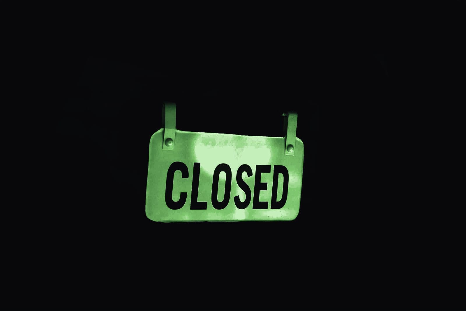 A closed sign hanging in a darkened doorway